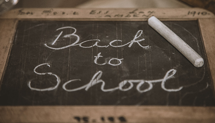 back to school written in chalk on a small hand held chalkboard