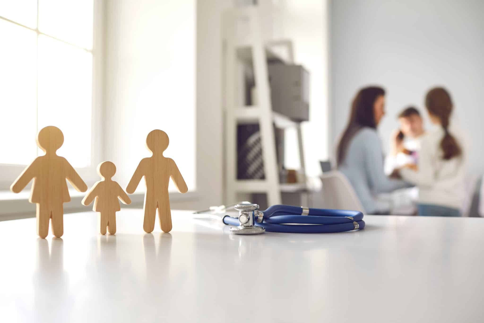 Stethoscope,With,Small,Wooden,Family,Member,Figures,Standing,On,Doctor's