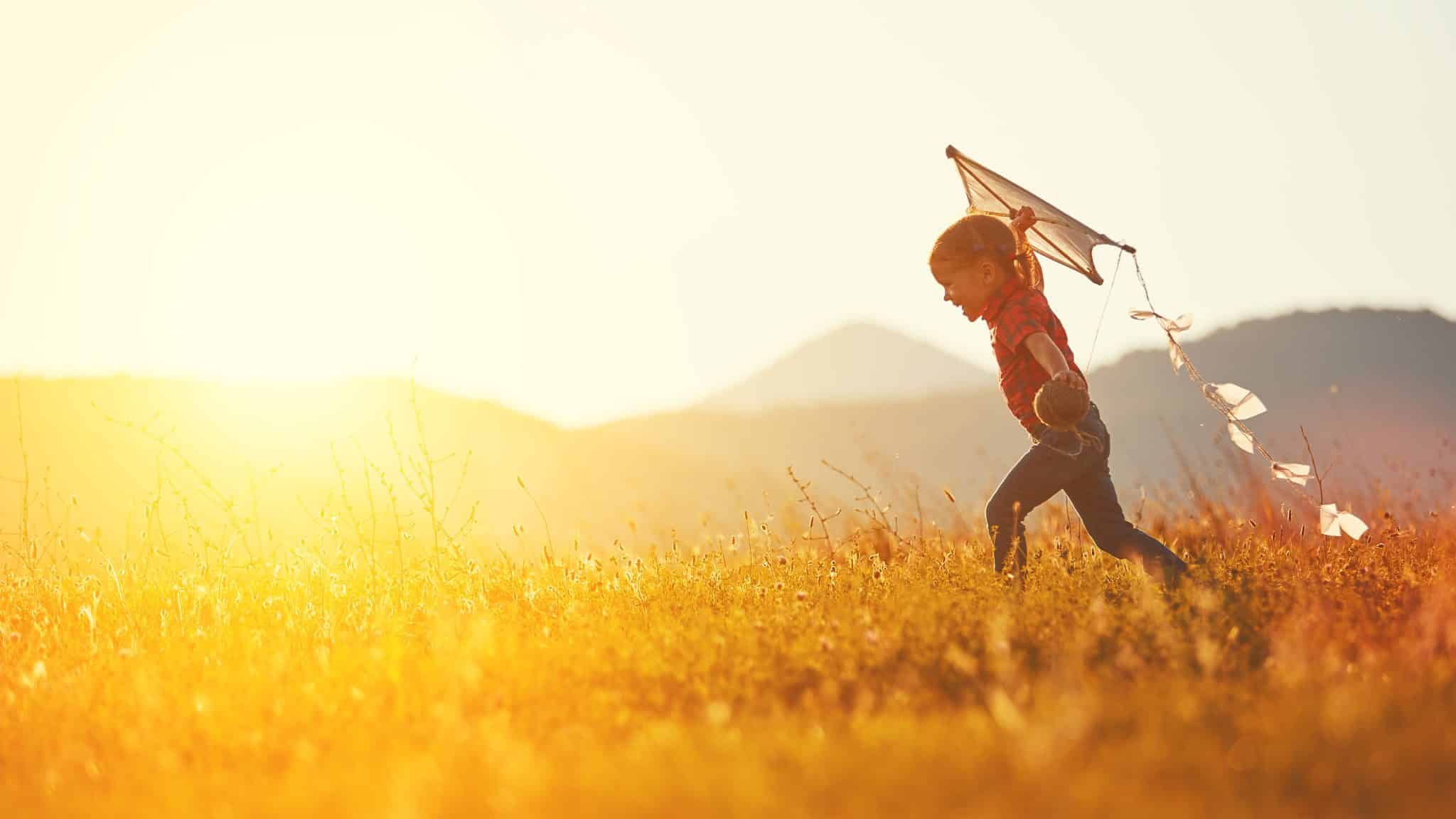 Happy,Child,Girl,With,A,Kite,Running,On,Meadow,In