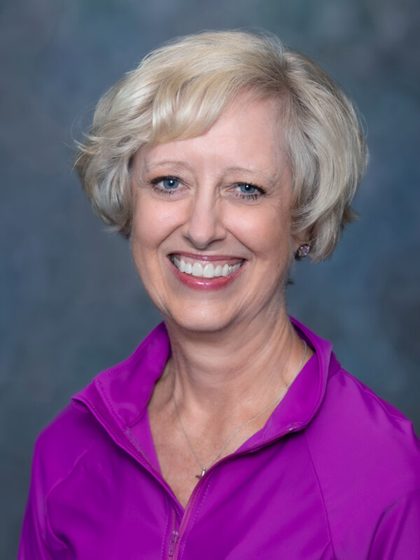 Headshot of Michele Welte, nurse practitioner at South Lake Pediatrics. Michele has short blonde hair, is wearing a bright pink top, and is smiling at the camera.