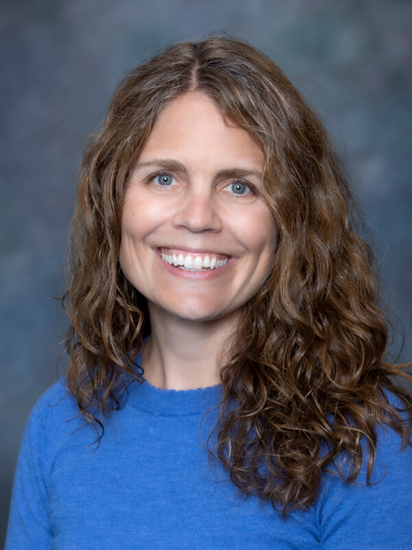 Headshot of Alison Brophy, pediatrician at South Lake Pediatrics. Alison has curly brown hair, is wearing a blue top, and is smiling at the camera.