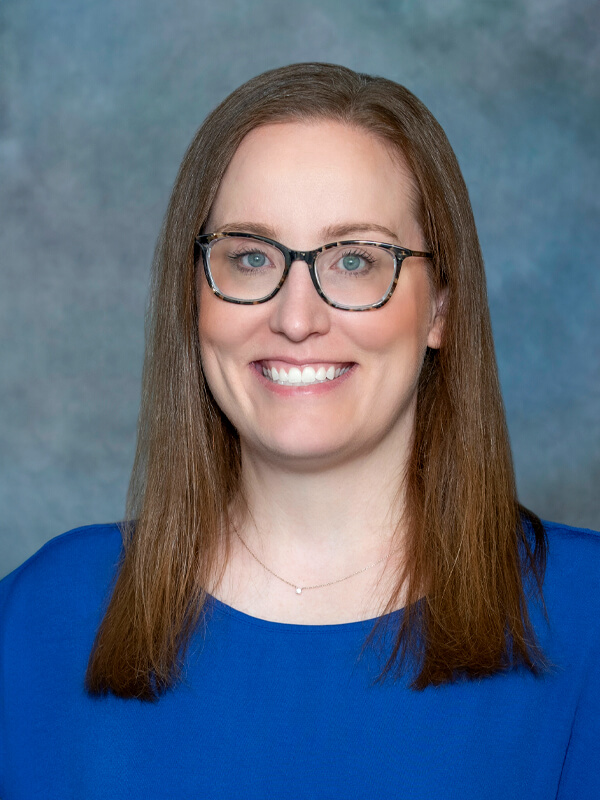 Headshot of Jenna Tassi, pediatrician at South Lake Pediatrics. Jenna has straight brown hair, is wearing glasses and a blue top, and is smiling at the camera.