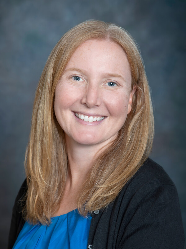 Headshot of Julie Ewasiuk, pediatrician at South Lake Pediatrics. Julie has long blonde hair, is wearing a black cardigan over a blue top, and is smiling at the camera.