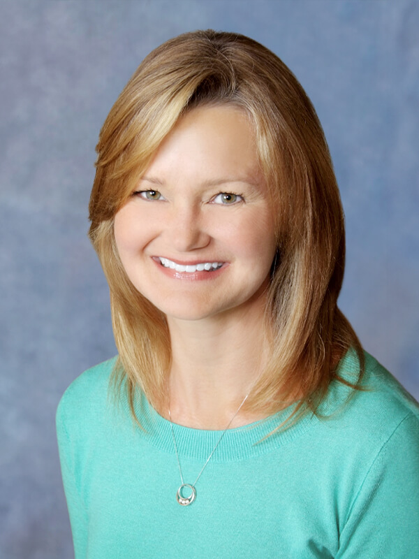 Headshot of Lisa Batchelor, pediatrician at South Lake Pediatrics. Lisa has long blonde hair, is wearing a black blazer over a mint green top, and is smiling at the camera.