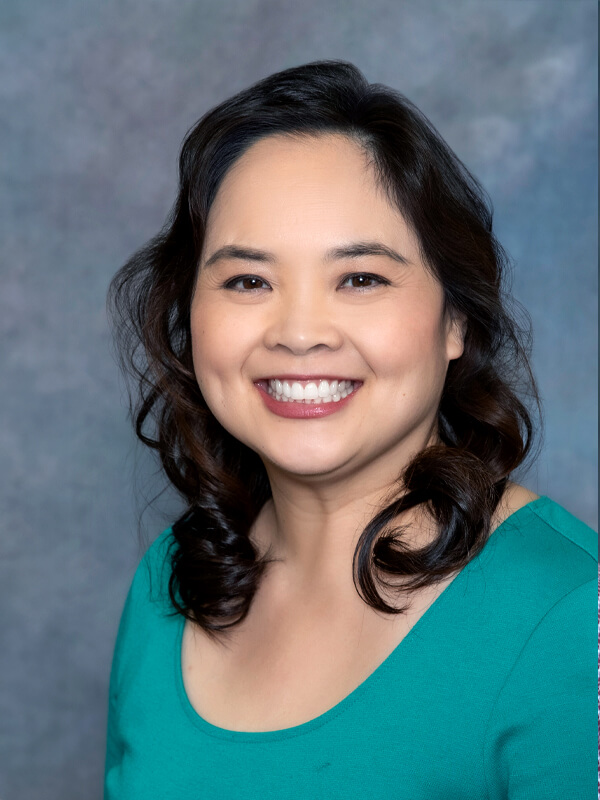 Headshot of Megan Wong, pediatrician at South Lake Pediatrics. Megan has long black hair, is wearing a green top, and is smiling at the camera.