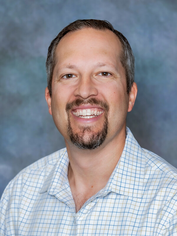 Headshot of Michael Magalnick, pediatrician at South Lake Pediatrics. Michael has short grey hair, is wearing a grey polo shirt, and is smiling at the camera.