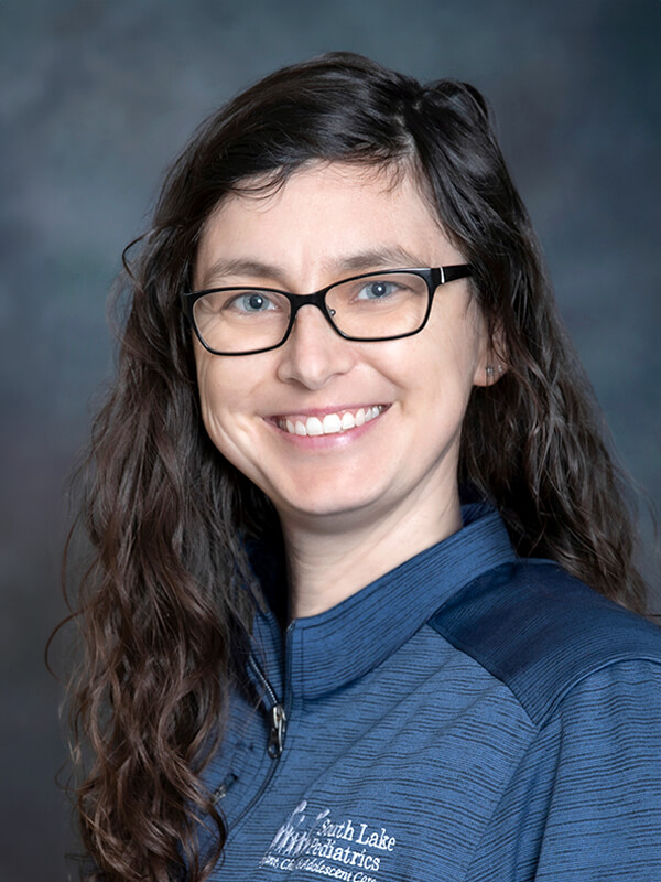 Headshot of Nathalie Lechault, pediatrician at South Lake Pediatrics. Nathalie has long brown hair, is wearing a dark top, and is smiling at the camera.