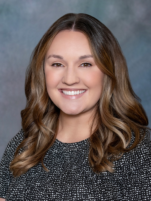 Headshot of Alycia Midas, pediatrician at South Lake Pediatrics. Alycia has long brown hair, is wearing a black top, and is smiling at the camera.